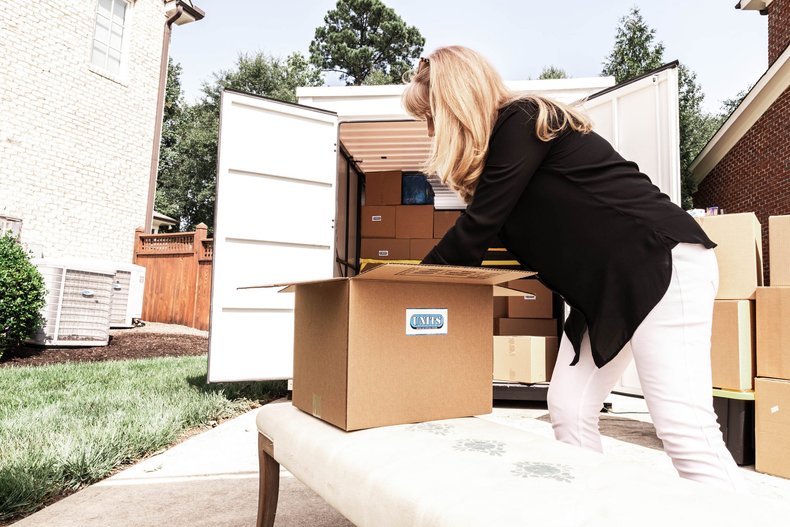 A woman packing boxes with the units logo on them into a container.