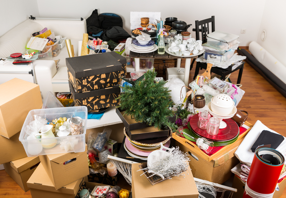 A cluttered living room with boxes on the floor.