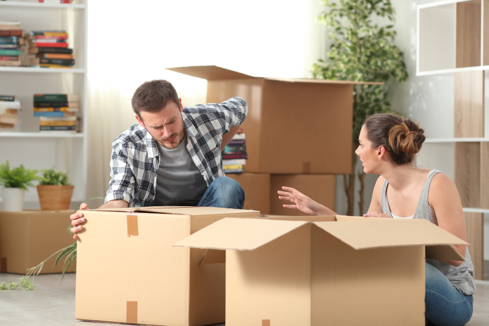 A couple unpacking items from boxes into their new house.