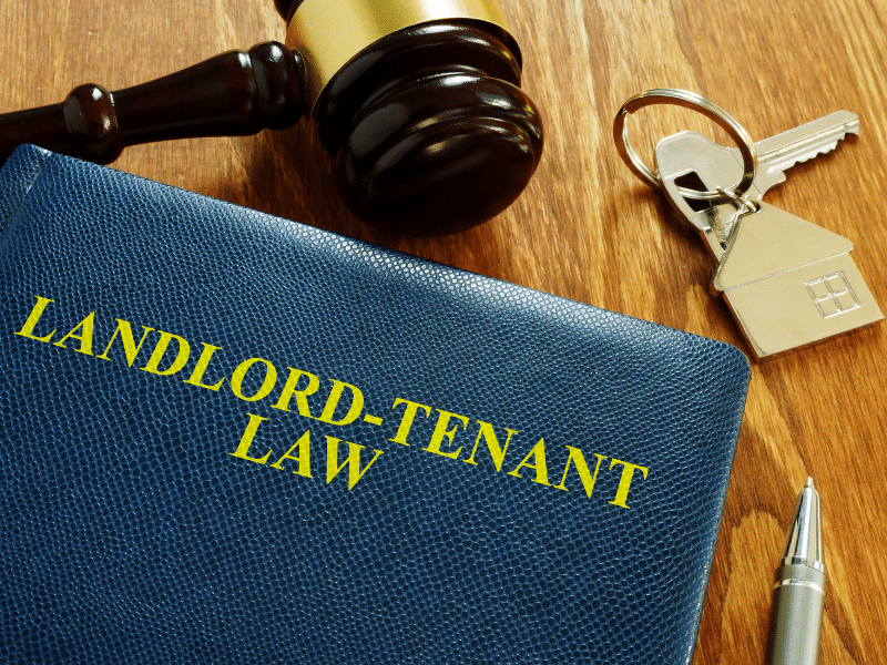 A book that is labeled Landlord - Tenant Law with keys and a gavel next to it.