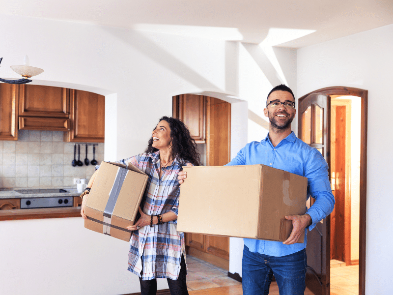 A couple carrying boxes into their new house.