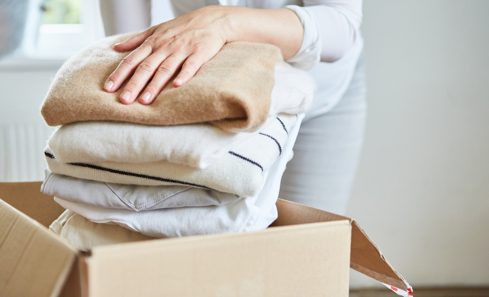 Woman storing away towels in a cardboard box.