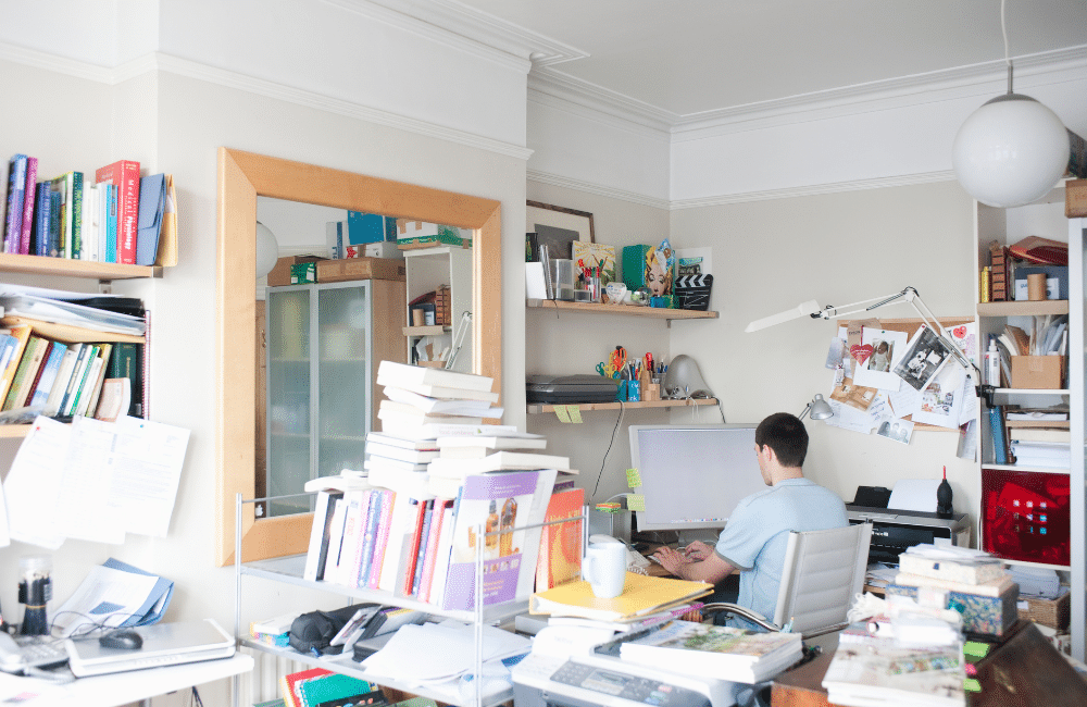 Man sitting inside of a cluttered room.