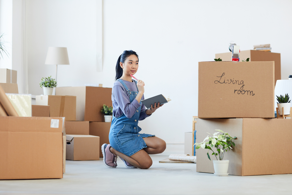 Woman kneeling on the floor wondering what to do with the cardboard boxes around her.