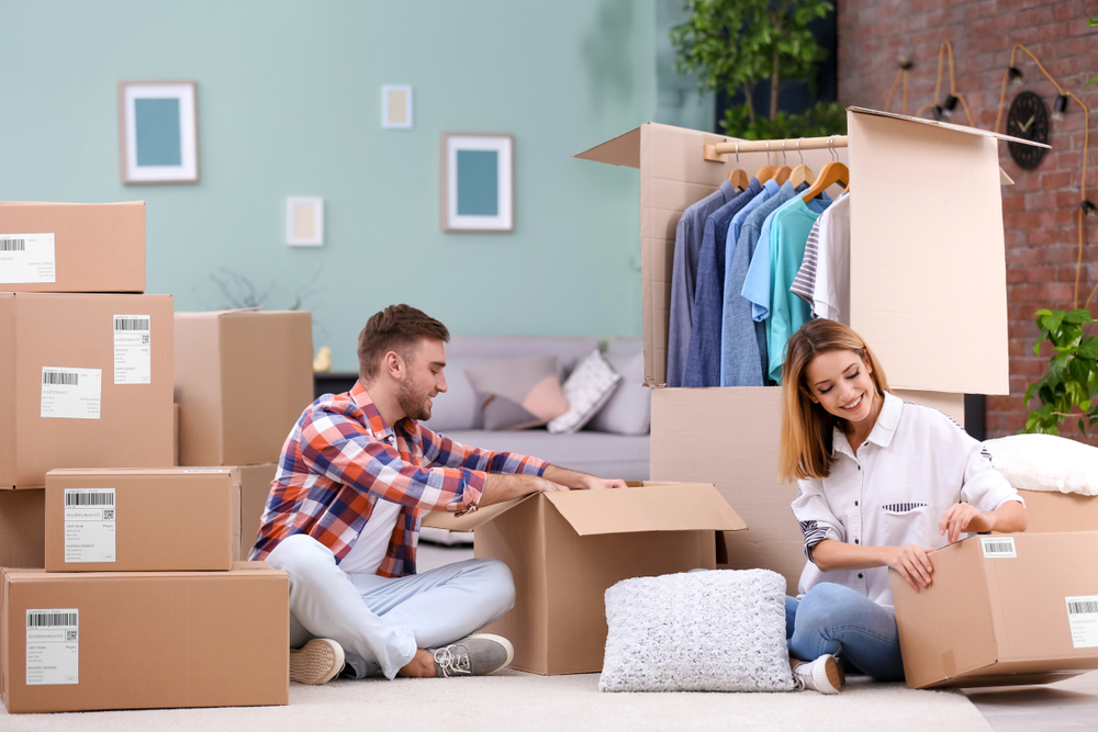 Man and woman sitting on the floor going through cardboard boxes.