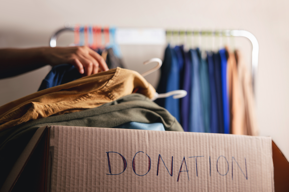 Person putting clothes into a cardboard box labeled Donation.