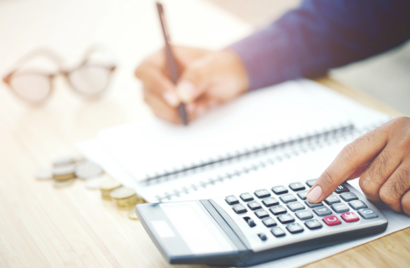 Person using a calculator and writing in a notebook.