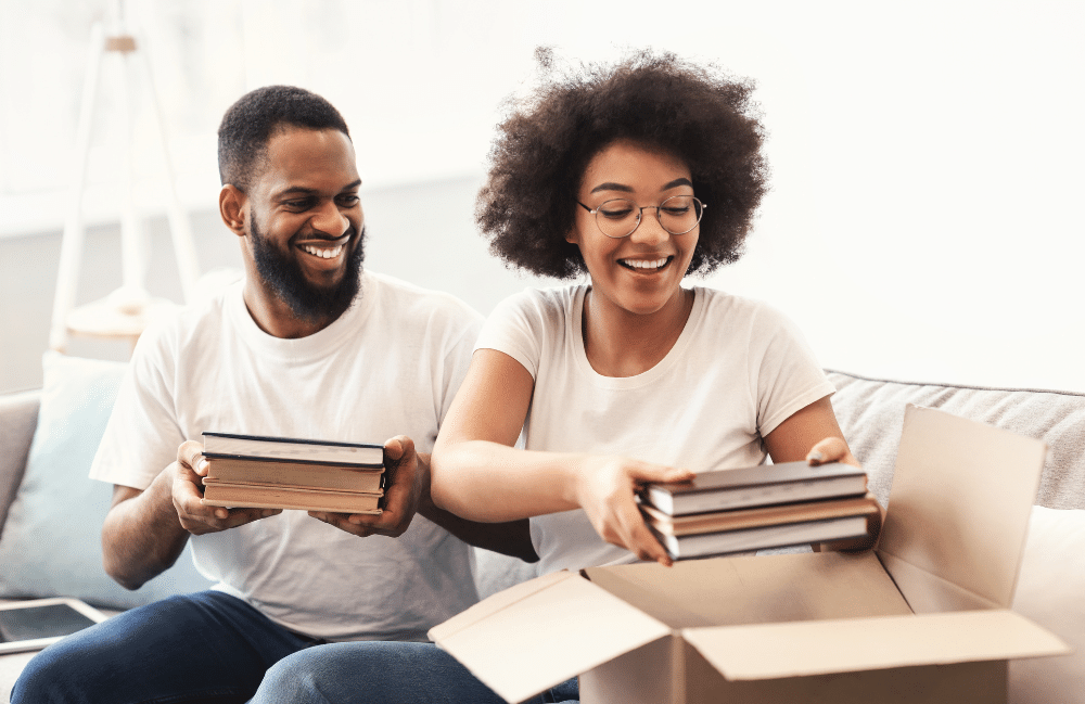 Couple packing books into a cardboard box.