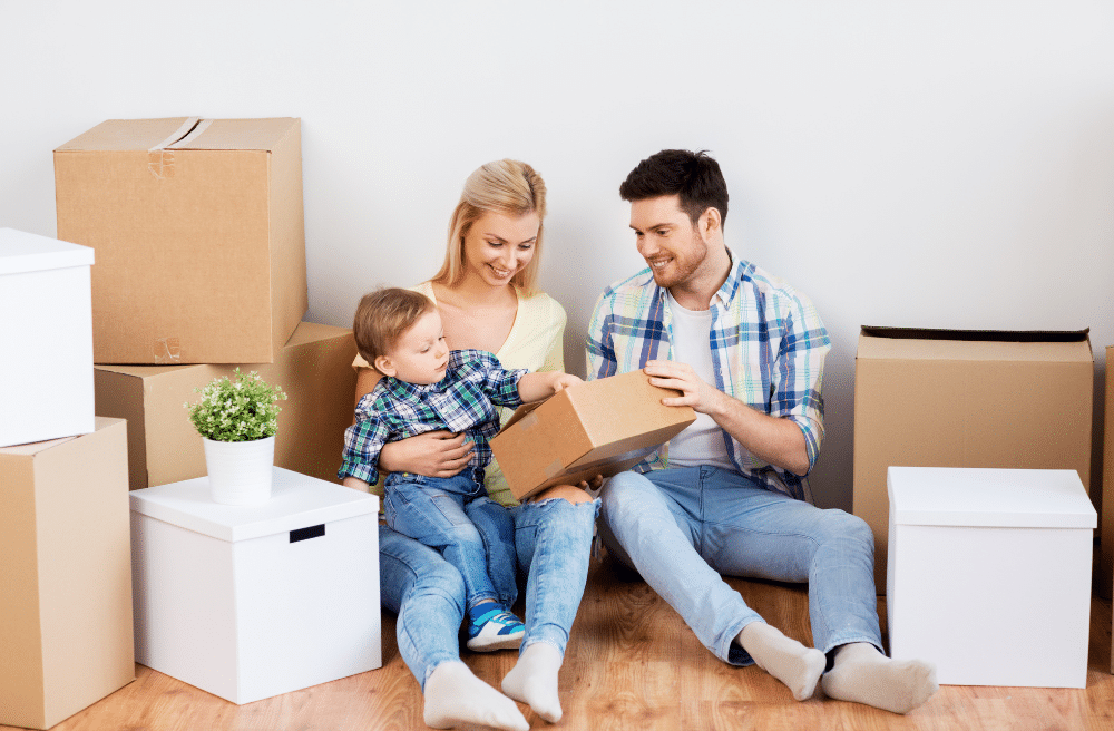 Man and woman showing a cardboard box to their young son.