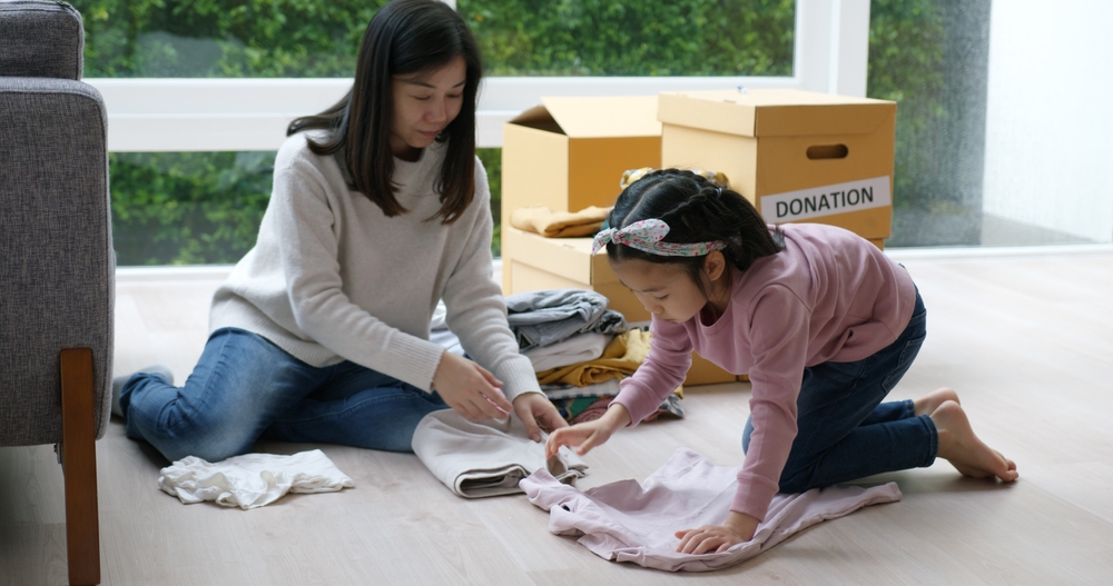 Woman folding laundry on the floor with her young daughter.