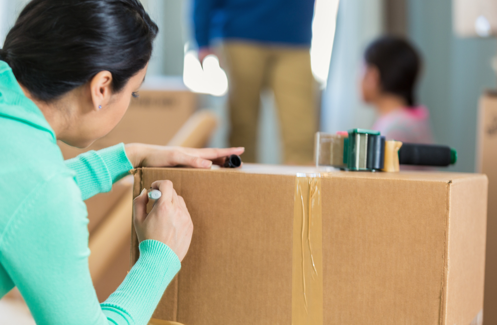 Woman writing on a cardboard box with a marker.