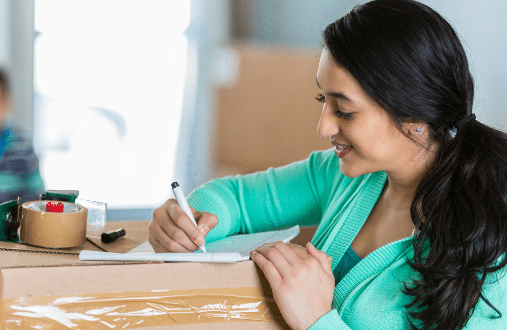 Woman writing on a paper notepad while sitting on the floor.