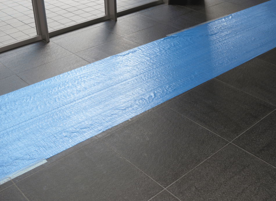 Blue tape over a black tile floor.