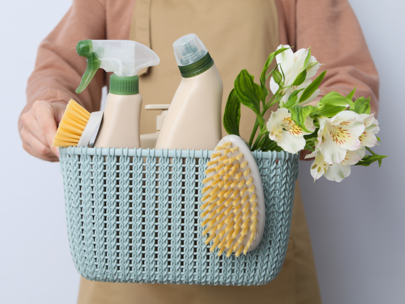 a person holding a basket of Spring Cleaning supplies