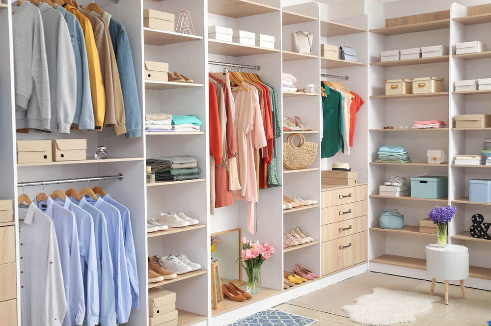 Large closet filled with clothes on hangers, bags and drawers on shelves.