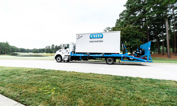 ROBO-UNIT moving a UNITS Moving and Portable Storage container off a truck.