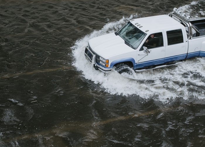 A truck driving through water on a flooded street.