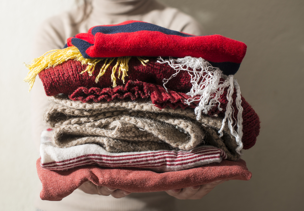 A woman holding multiple folded blankets in her hands.