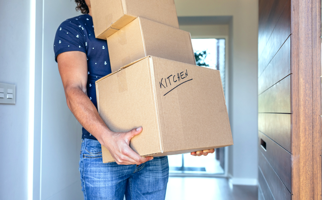 A man holding multiple boxes with one labeled kitchen.