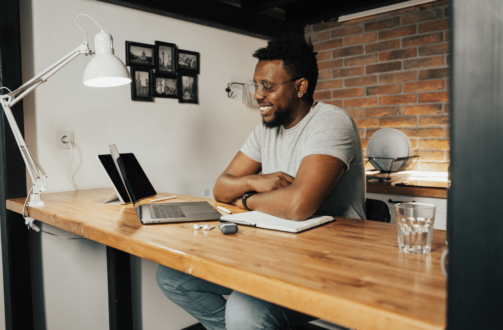 A man sitting at a counter in front a his laptop and I pad.