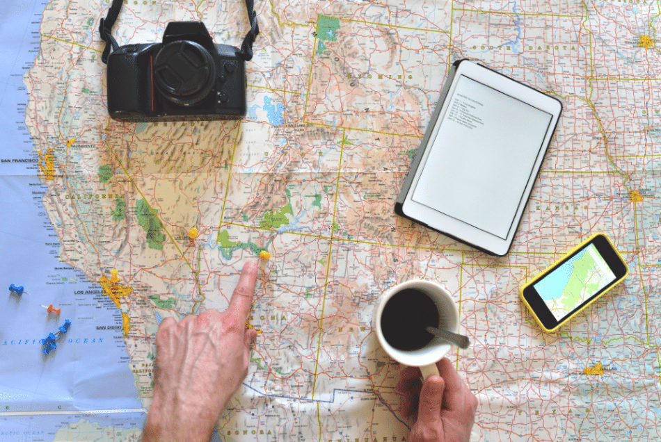 Someone planning a trip on a map with a cup of coffee.