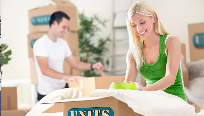 Happy couple unpacking their UNITS Storage cardboard boxes.