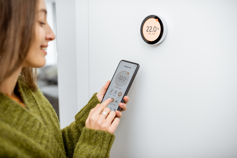 Woman adjusting her thermostat with her phone.