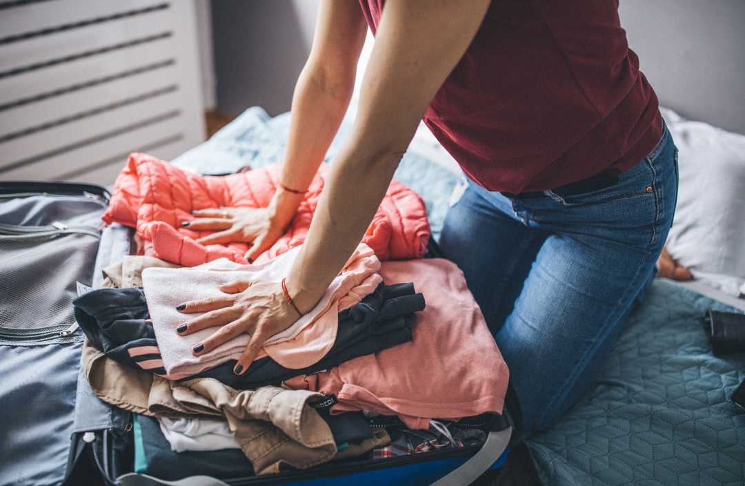 Woman packing a suitcase with clothes.