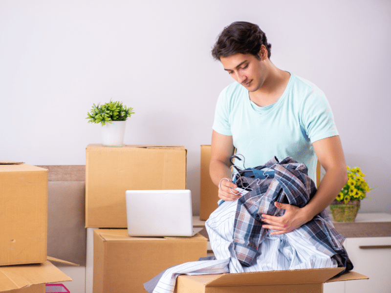 Man packing clothes in a cardboard box to be moved.