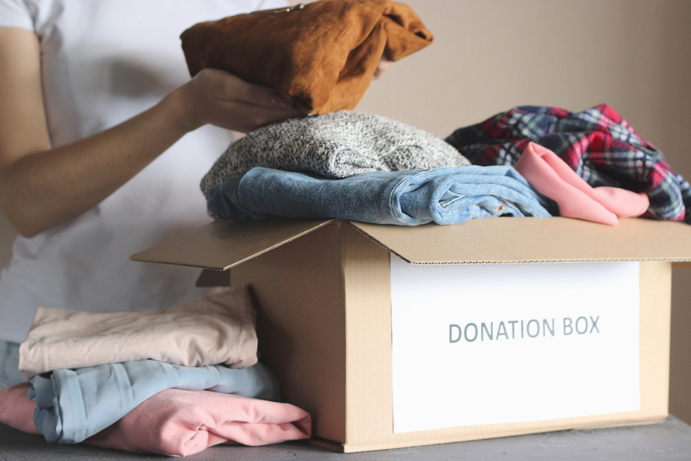 A person packing items into a box labeled donation box.