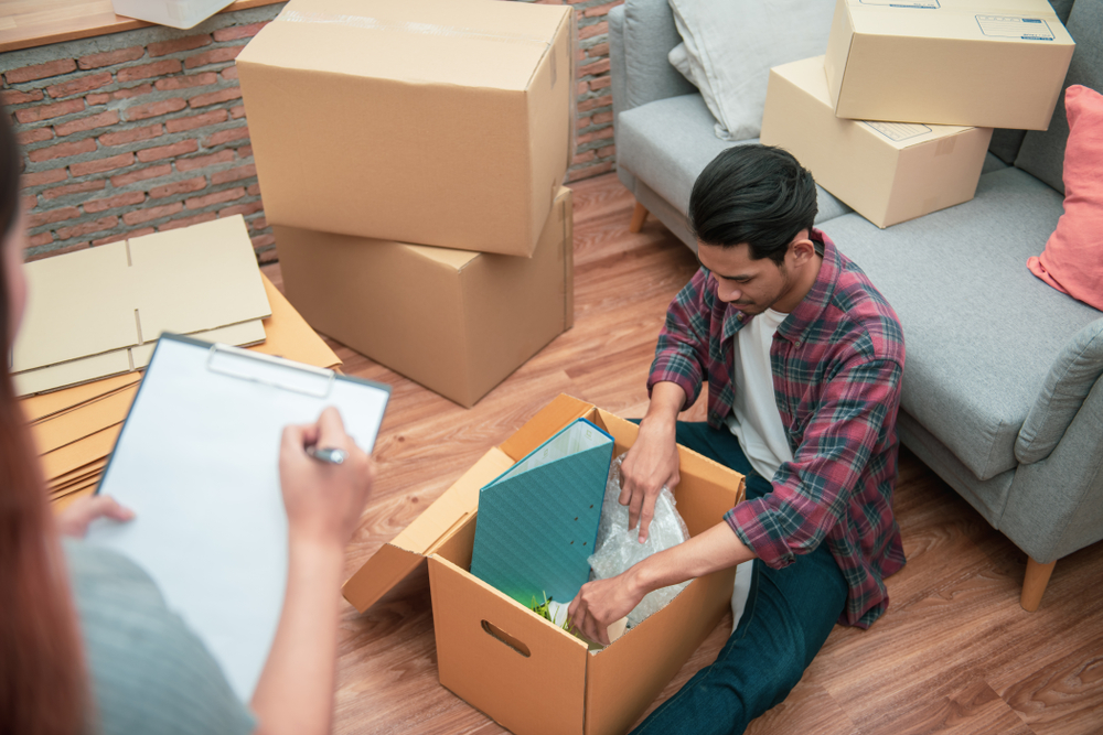 A man packing items into a box and a woman checking boxes off a list.