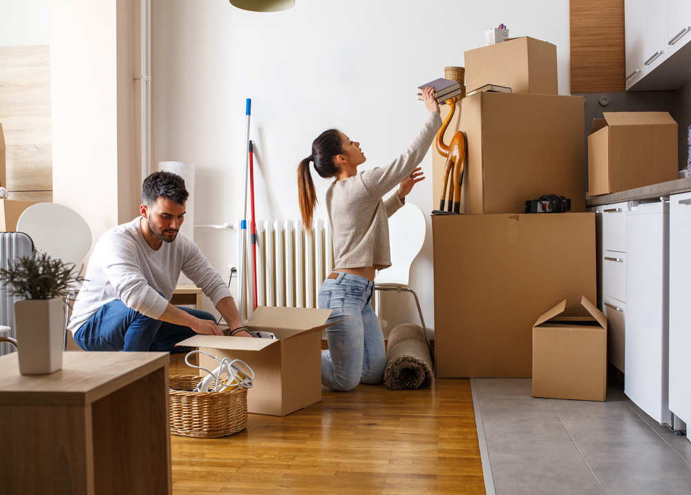 A couple packing boxes on the ground surrounded by boxes.