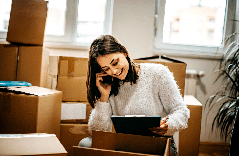 A woman looking at a checklist surrounded by boxes.