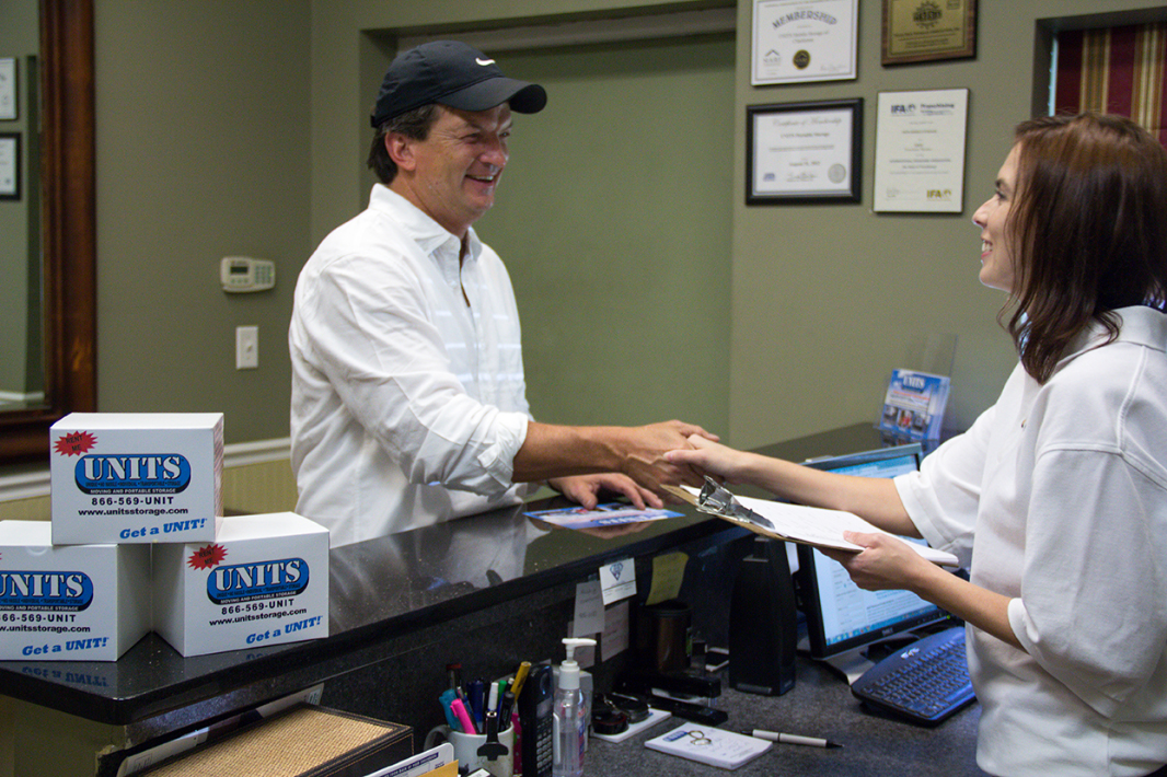 Woman shaking a mans hand with Units business cards in the back.