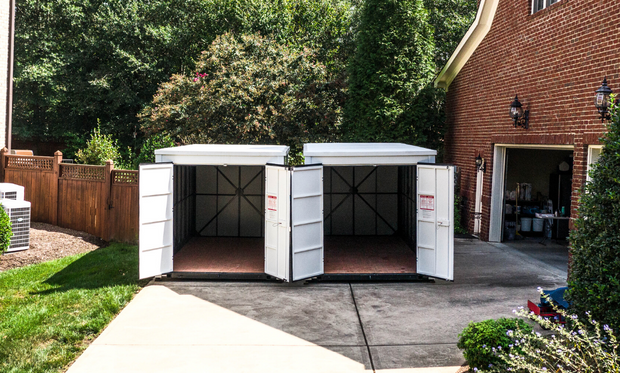 Two containers sitting in a driveway with their doors open.