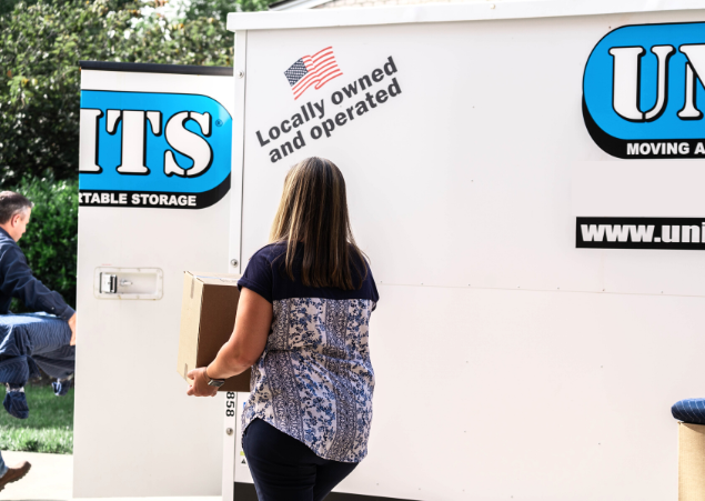 A woman moving a box into a Units Of Louisville container.