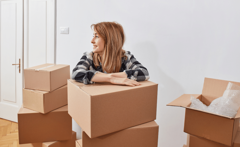 Woman with her arms crossed on a box surrounded by boxes.