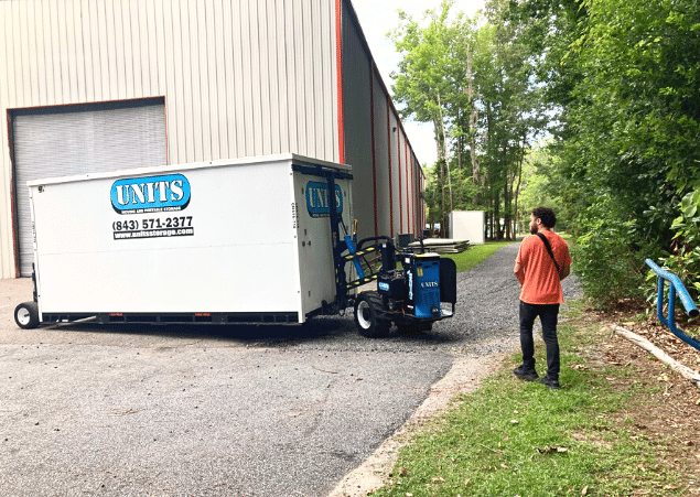 A man standing in front of a Units of North Shore container.