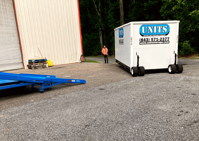 A Units of North Shore container outside with a man standing next to it.