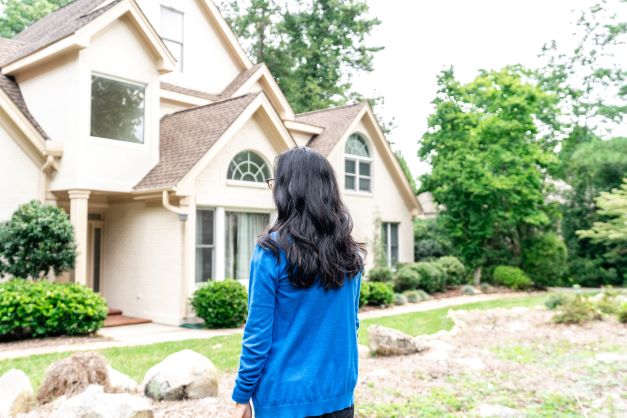 A woman standing in front of a house.