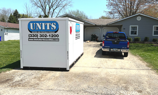 A Units Of Northeast Ohio container sitting in the driveway of a house.