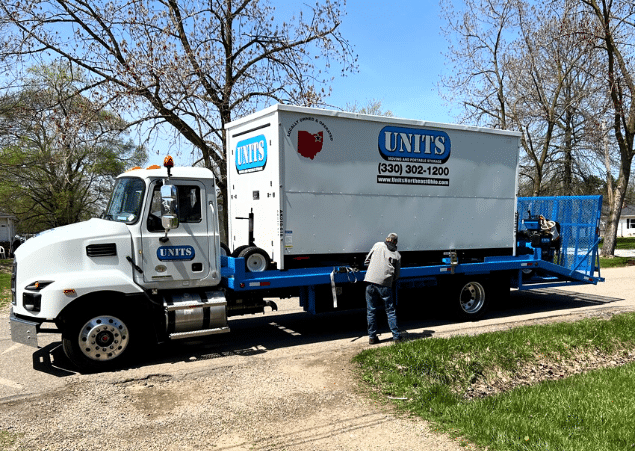 A man standing in front of a Units Of Northeast Ohio container.