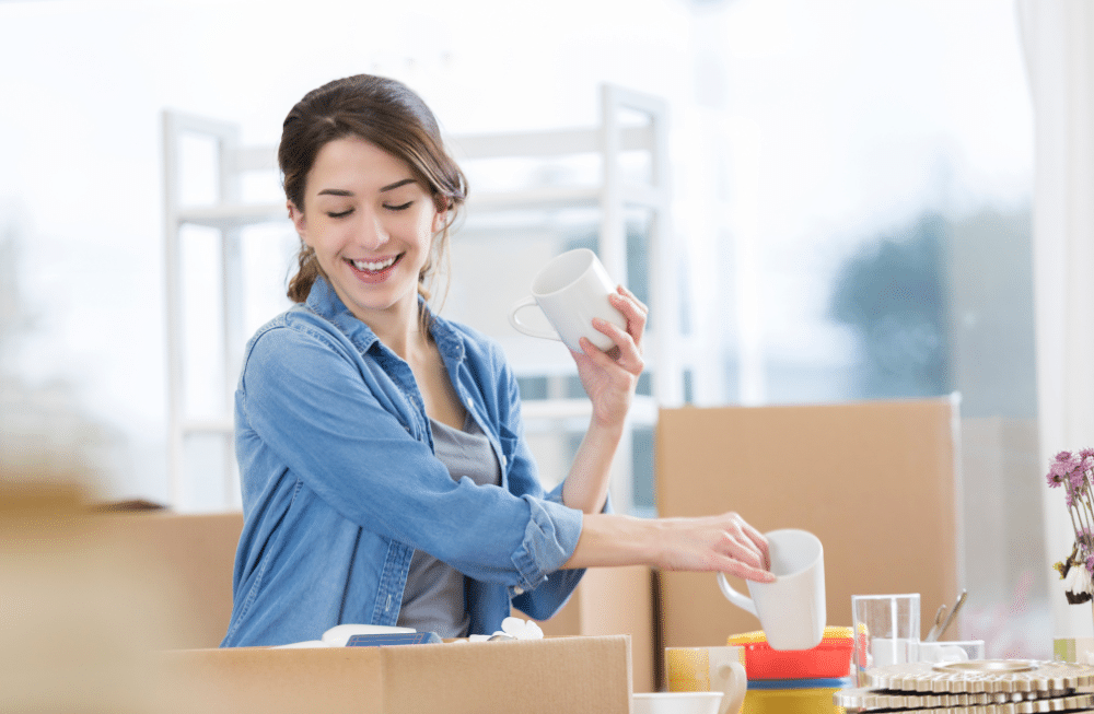 A woman unpacking items from boxes in her kitchen.