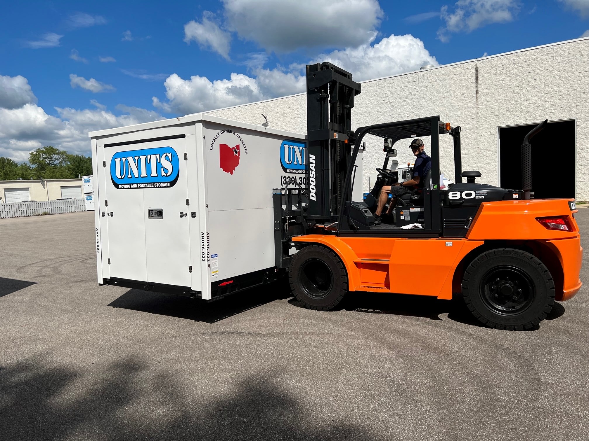 A man moving a Units Of Northeast Ohio container with a forklift.