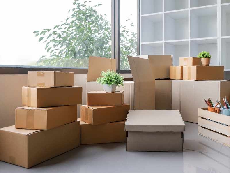 Cardboard boxes stacked on the ground in a living room.