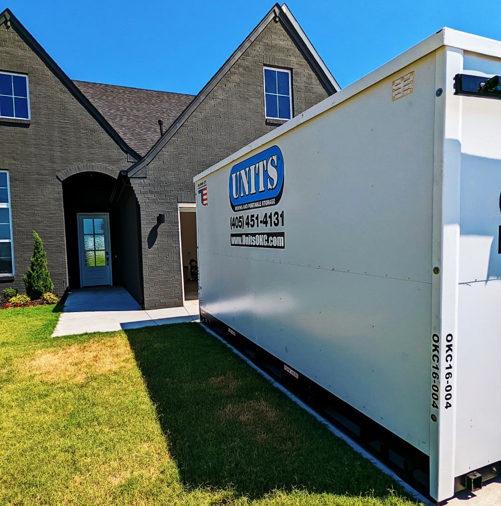 A Units of Oklahoma City container sitting in the driveway of a house.