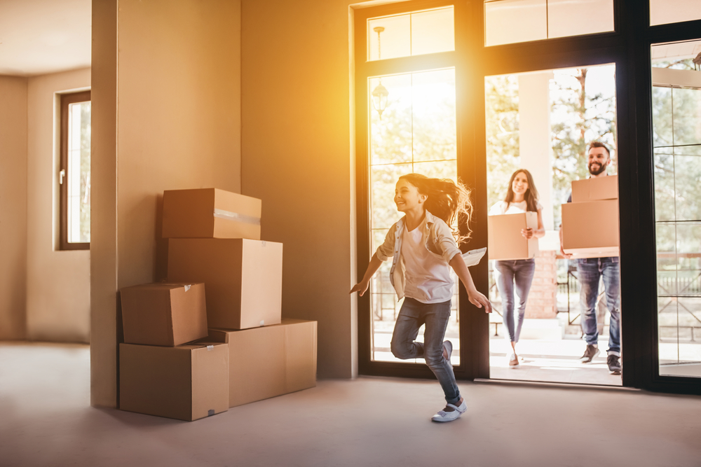 A family moving into a new house holding boxes.