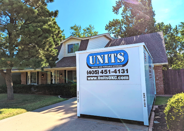 A Units of Oklahoma City container sitting in the driveway of a house.