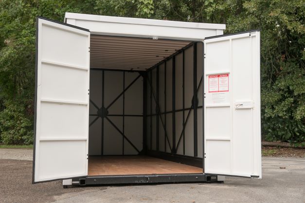 A container sitting on the ground with its doors open.