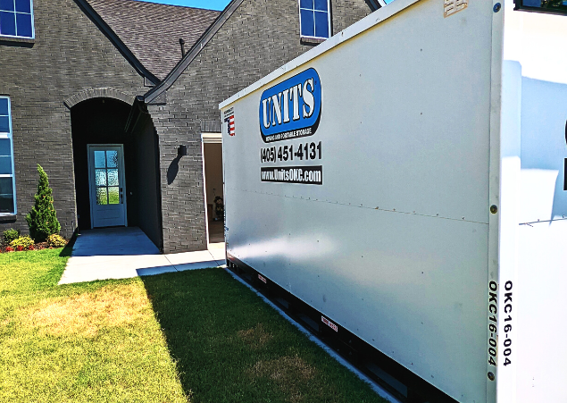 A Units of Oklahoma City container sitting in the driveway of a house.